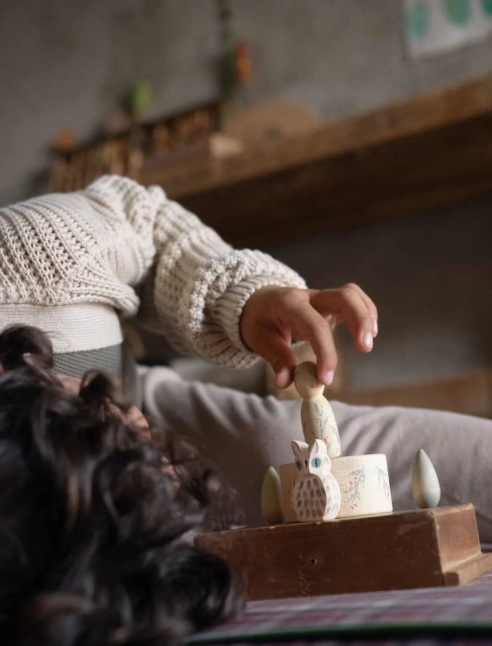 Child playing with a wooden toy in a cozy indoor setting